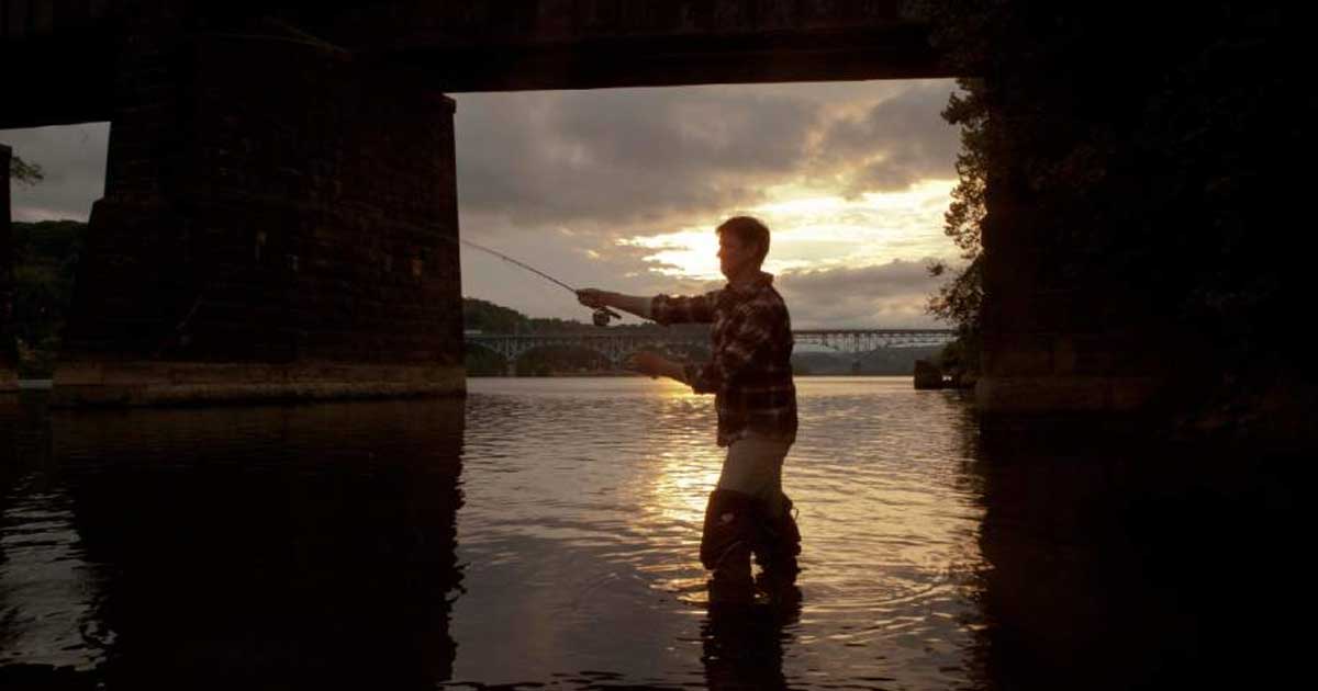 Actor fishing in the river at dusk
