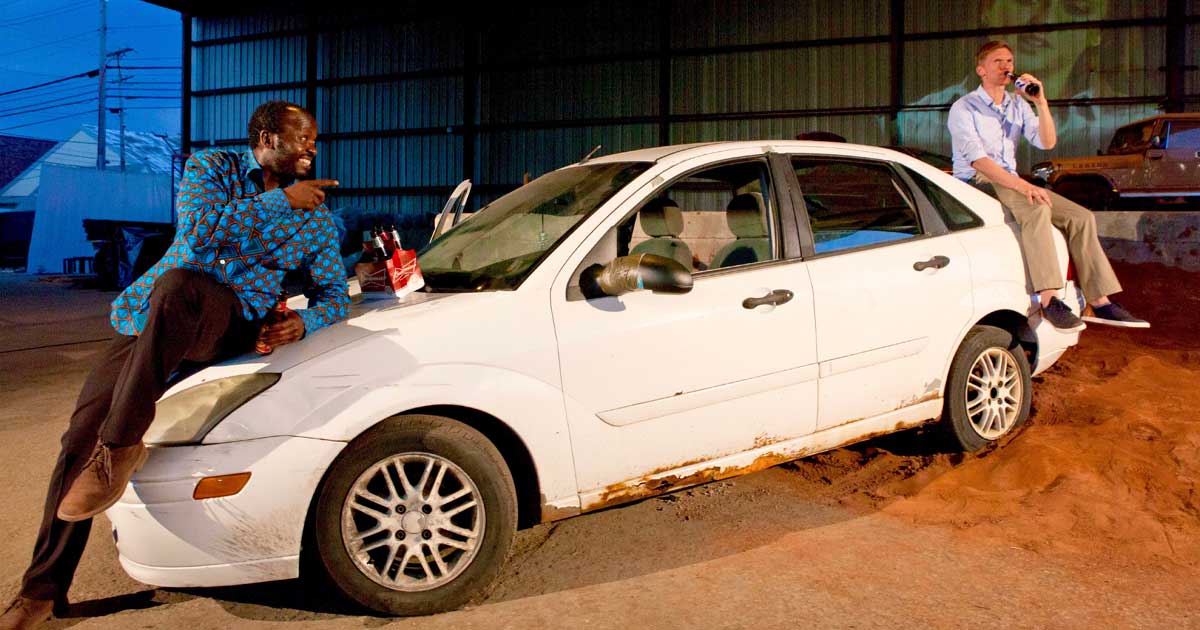 actors talking while sitting on a car