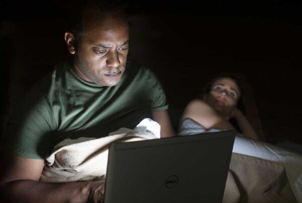 Actor looks at computer in bed