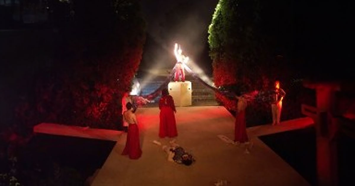 Actors in red on outdoor stage